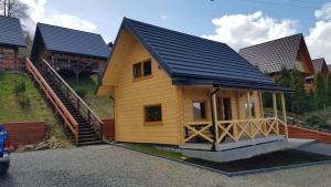 a small wooden house with a black roof at Domek u Pusi z jacuzzi in Solina +23 photos