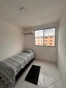 une petite chambre avec un lit et une fenêtre dans l'établissement Viver Melhor Apartment, à Marituba