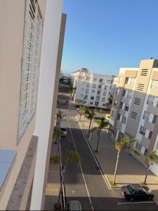 Blick auf eine Straße mit Palmen und Gebäuden in der Unterkunft Blue Ocean Escape Sidi Rhal in Sidi Rahal