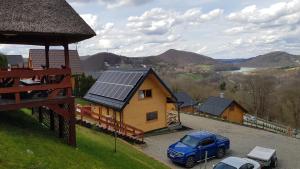 a blue car parked in front of a house with solar panels at Domek u Pusi z jacuzzi in Solina