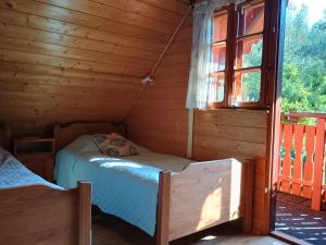 two beds in a log cabin with a window at Sielski Zakątek in Piecki