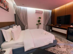a hotel room with a white bed and a flat screen tv at Aurum on Missouri in Abuja