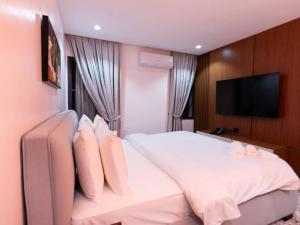 a bedroom with a white bed with a flat screen tv at Aurum on Missouri in Abuja
