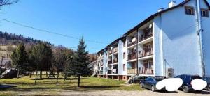 ein großes Gebäude, vor dem Autos parken in der Unterkunft Bieszczady Apartament Gniazdo Baligród in Baligród