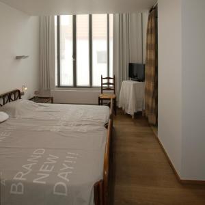 een slaapkamer met 2 bedden, een tafel en een televisie bij B&B 't Walleke in Brugge
