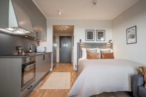 a bedroom with a bed and a kitchen at Injoy Premium Hotel Uppsala in Uppsala +20 photos