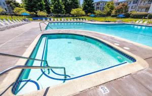 a large swimming pool with blue water and chairs at Waterfront Apartment Minutes to San Francisco in Emeryville +4 photos
