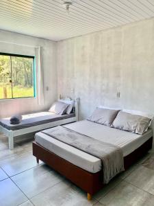 a bedroom with two beds and a window at Cada na Praia Itapeva Torres in Torres