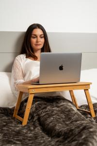 una mujer sentada en una cama con un portátil en una mesa en Alpha Studios Naxos - Adults Only, en Naxos Chora