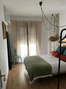ein Schlafzimmer mit einem Bett und einem Stuhl und einem Fenster in der Unterkunft Apartamento CASA PEPA in Antequera
