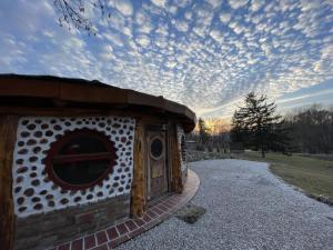 a dog house on a gravel road with a cloudy sky at Őze Hobbitház in Bárdudvarnok