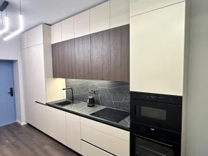 a kitchen with white cabinets and a black appliance at Lauvas Rezidences - Self check-in in Rīga