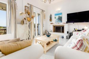 a living room with white furniture and a fireplace at Villa Meliti Paros in Angairiá