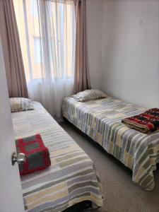 two beds sitting next to a window in a room at Noruega in La Serena