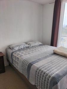 a bedroom with a bed with a blanket and a window at Noruega in La Serena +2 photos