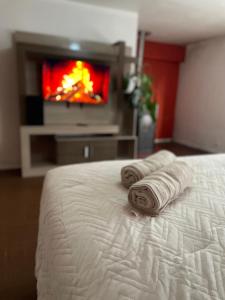 a bedroom with a bed with two rolled towels in front of a tv at Hostal lynch in Osorno