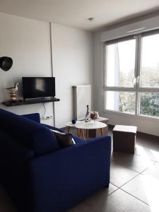 a living room with a blue couch and a table at Charmant studio vue dunes à 400m de la plage in Dunkerque