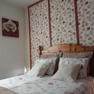 a bedroom with a bed with a wooden headboard and pillows at Les 4 Portes in Le Mesnillard