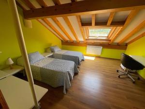 a attic room with two beds and a window at Casa pareada rural Elechino in Entrambasaguas
