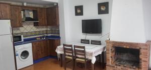a kitchen with a table and a fireplace with a microwave at Casa Curro in Benaocaz +3 photos