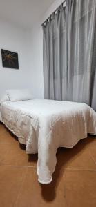 a white bed in a room with a curtain at Casa Curro in Benaocaz