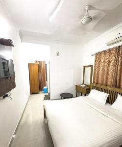 Un dormitorio con una gran cama blanca en una habitación. en Sathya Inn Guruvayur, en Trichūr