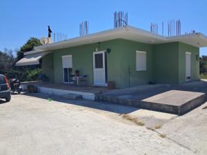 a green house with a car parked in front of it at Galinis Rooms in Paradeísion +8 photos