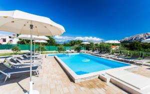 ein Swimmingpool mit Stühlen und einem Sonnenschirm in der Unterkunft Apartments Lucija in Baška