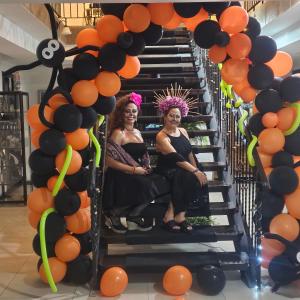 エレディアにあるBrisas del Aeropuerto Airport Breezes innのオレンジと黒の風船を持って階段に座っている2人の女性