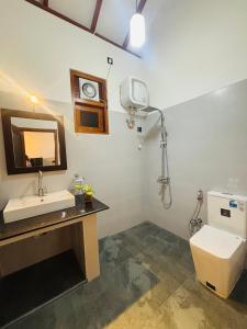a bathroom with a sink and a toilet and a mirror at Rock Harmony Villa in Hikkaduwa