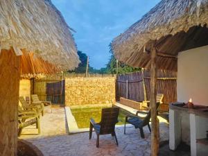 Un patio con sillas y una mesa y un techo de paja. en Kogui Aldea, en Palomino