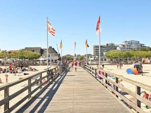 a pier with people on the beach and flags at 6 person holiday home in Großenbrode in Großenbrode