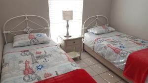 a bedroom with two beds and a lamp at Strandloper Apartments in Hermanus