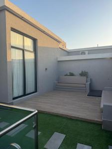 a patio with a bench and grass in front of a building at شاليهات أجواء الريف in Dammam