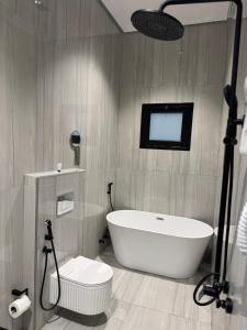 a bathroom with a tub and a tv on the wall at شاليهات أجواء الريف in Dammam