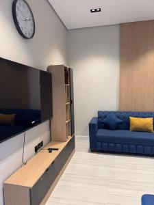 a living room with a blue couch and a clock on the wall at شاليهات أجواء الريف in Dammam +34 photos