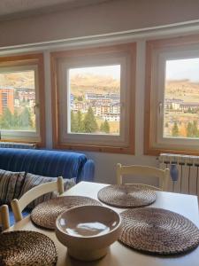a table with four chairs and two windows at Casa Dolce Presena in Passo del Tonale