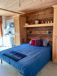 ein Schlafzimmer mit einem blauen Bett und einer Holzwand in der Unterkunft Grand Studio Val Cenis in Lanslebourg-Mont-Cenis + 14 Fotos