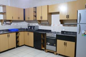 cocina con armarios de madera, fogones y nevera en Home away from home, en Kigali