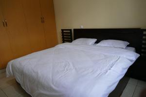 1 cama blanca grande con sábanas y almohadas blancas en Home away from home, en Kigali
