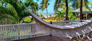 a hammock on a deck with palm trees and the ocean at Casa Janjão in Icaraí