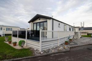a small white house with a white fence at Starlings Nest at Hamilton Lodge in Kinmel Bay