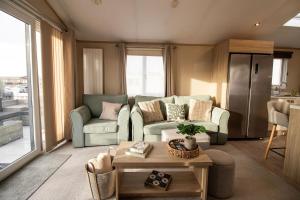 a living room with two couches and a table at Starlings Nest at Hamilton Lodge in Kinmel Bay