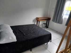 een slaapkamer met een bed, een tafel en een raam bij Apartamento bem localizado São Sebastião - SP in São Sebastião