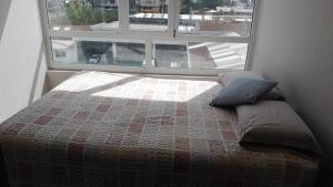 a bed with a quilt on it in front of a window at Departamento 610 in Temuco