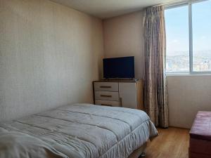 a bedroom with a bed and a tv and a window at Hampiwasi in Miraflores
