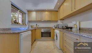 a kitchen with wooden cabinets and a dishwasher at Beachside oasis with Pool in Luz
