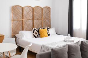 Un dormitorio con una gran cama blanca con almohadas. en Estudio Centro de Sevilla, en Sevilla