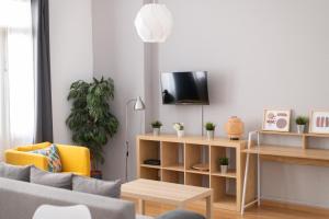 Una sala de estar con un sofá y un televisor en una pared. en Estudio Centro de Sevilla, en Sevilla