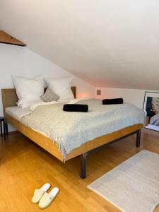 a bedroom with a bed with two slippers on the floor at Soleils Living I See & Berge I Starnberger See in Berg am Starnberger See +40 photos